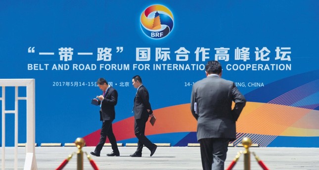 People walk past a billboard for the Belt and Road Initiative (BRI) forum, at the venue for the meeting in Beijing, May 11, 2017.